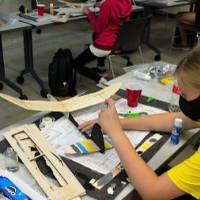 A camper paints her wooden airplane